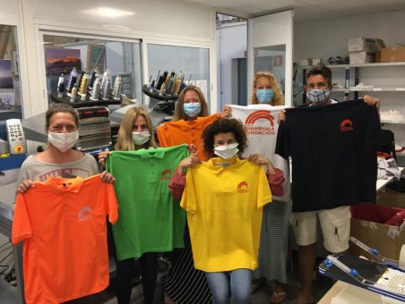Youngsters in an office showing their different coloured new polo shirts