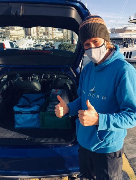 A man doing thumbs up behind a car