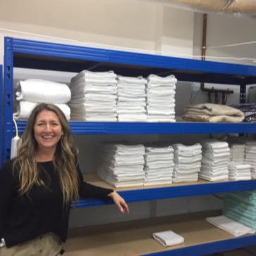 A woman next to a stacked up linen storage at the shelter Llar Kurt