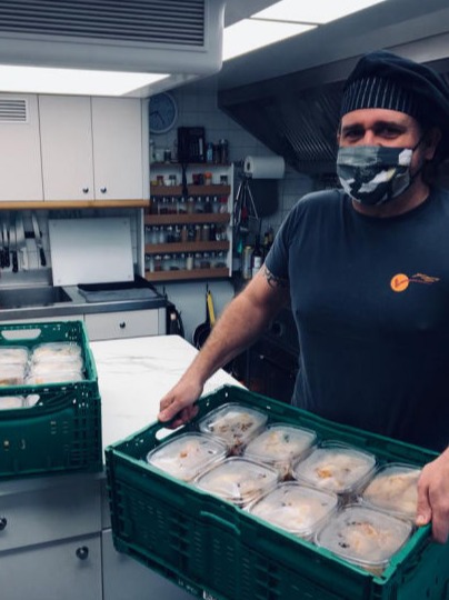A chef standing in the galley holding a basket of food rations