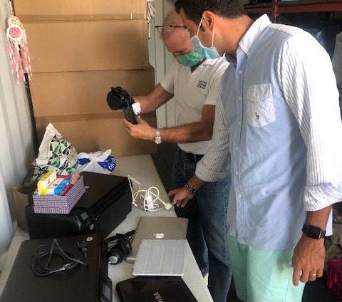 Two men inspecting donated printers at the YGB container