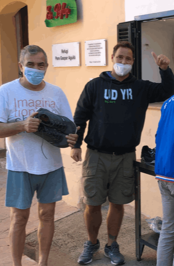Two smiling men receive donated shoes