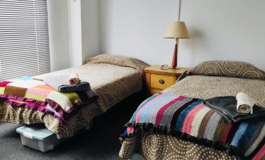 Two neatly made beds  side by side in a dormitory