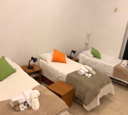 3 neatly made beds in a dormitory at the shelter Llar Inge