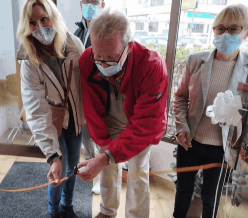 A man cutting a red ribbon at the opening of the shelter