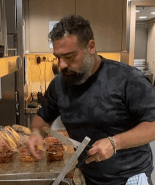 Two yacht chefs show the ready made meals they have prepared for the food bank