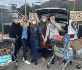 A group of people in front of a car, bringing a donation