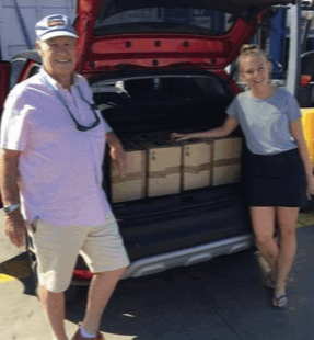 A man and a woman leaning on an open car boot