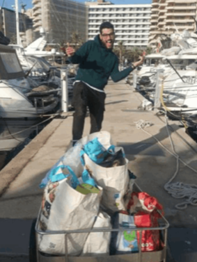 A smiling man on a dock with a trolley full of donations