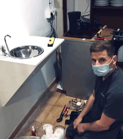 A man installing a drinking fountain at the shelter Llar Kurt